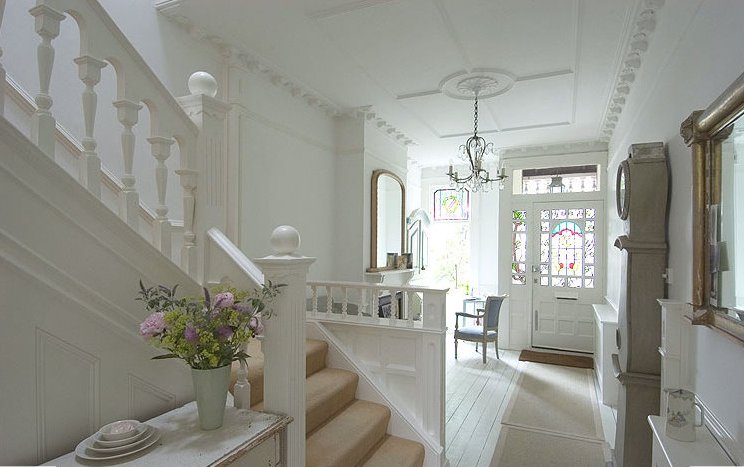 Edwardian house in England, showing hallway furnished with a desk and even a fireplace surmounted by a mirror, with perhaps a bench seat to the right.